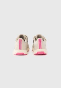 Μπεζ αθλητικά παπούτσια με ροζ λωρίδα στο πίσω μέρος, υφασμάτινη υφή και ροζ σόλα. Απλός σχεδιασμός με ουδέτερο χρωματικό συνδυασμό.