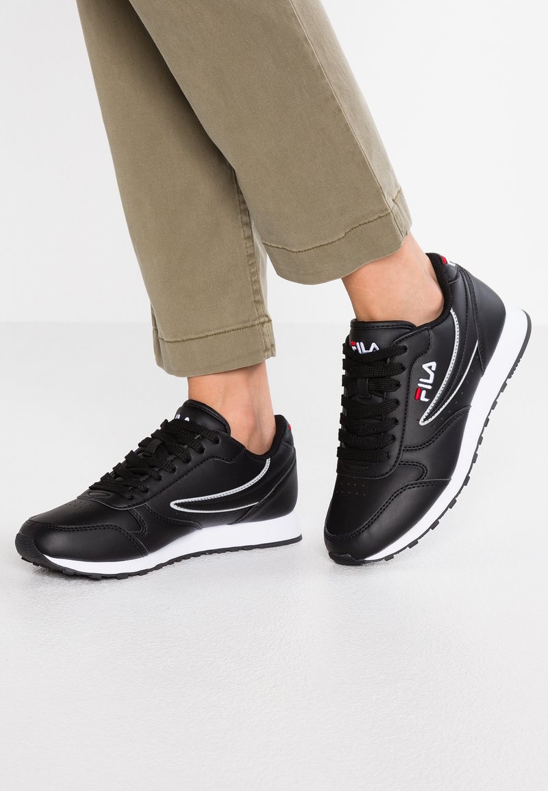 Black athletic shoes with silver accents, featuring a smooth synthetic upper, white midsole, and textured rubber sole.