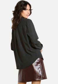 Long-sleeve, dark gray shirt with a loose fit and rounded hem, paired with a shiny, burgundy A-line skirt. Smooth texture and relaxed design.
