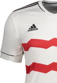 Witte voetbalshirt met rode zigzagstrepen, zwarte accenten en een Adidas-logo. Heeft een V-halsontwerp en korte mouwen.