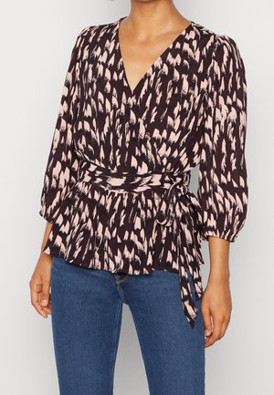 Schwarz-pink gemusterte Bluse mit V-Ausschnitt, Ballonärmeln und gebundenem Taillengürtel. Der Stoff hat eine weiche Textur und ein Peplum-Design.