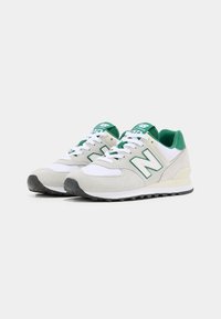 Zelené a bílé tenisky New Balance 574 vyrobené z nubukové a síťované látky, zaoblená špička, polstrovaný límec a černá gumová podrážka.