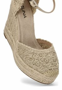 Espadrilles de yute tejido en color beige con punta cerrada, suela elevada de yute y correa de tobillo. Presentan un intrincado bordado a lo largo de la parte superior.