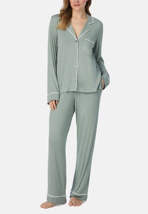 Ensemble de pyjama vert clair en tissu doux, comprenant un haut à boutons avec une poche et un passepoil blanc, associé à un pantalon ample.