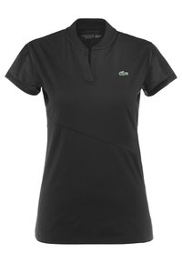 Svart kortärmad Lacoste Sport pikétröja med notch-krage och liten grön krokodil-logotyp på vänster bröst.