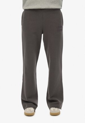 Szare bawełniane dresy o luźnym kroju, z haftowanym logo "Superdry Athletics" na lewej udzie oraz kieszeniami po bokach.