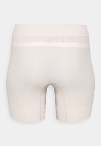 Beige sportshorts met een gladde textuur, duidelijke stiksels en een brede tailleband. Heeft een snit tot halverwege de bovenbenen en geen opvallende branding.