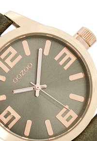 Montre à cadran vert avec de grands index en or rose, aiguilles argentées et finition texturée, présentant un boîtier métallique et une couronne sur le côté.