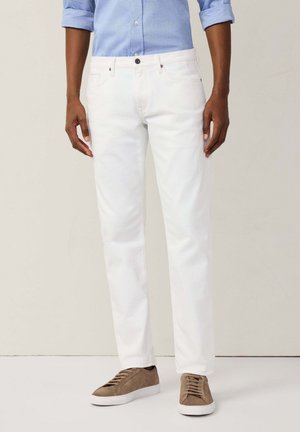 Witte denim broek met een rechte pasvorm, voorzien van voorzakken, een bovenste knop en bruine vetersneakers op een lichte achtergrond.