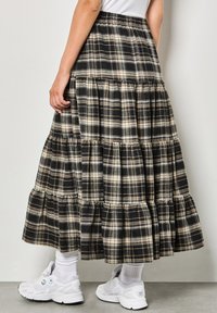 Gonna a balze nera e beige in tessuto morbido, con orlo arricciato e vita elastica. Abbinata a sneakers bianche.