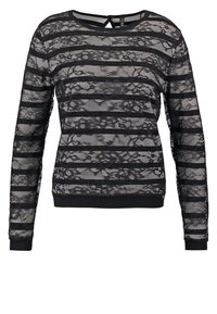 Sweat-shirt en dentelle noire à manches longues, présentant des motifs à rayures horizontales. Fini avec un ourlet et des poignets côtelés unis noirs.