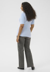 Haut à manches courtes en tricot côtelé bleu clair associé à un pantalon large gris. Le look présente une texture lisse et un design simple.