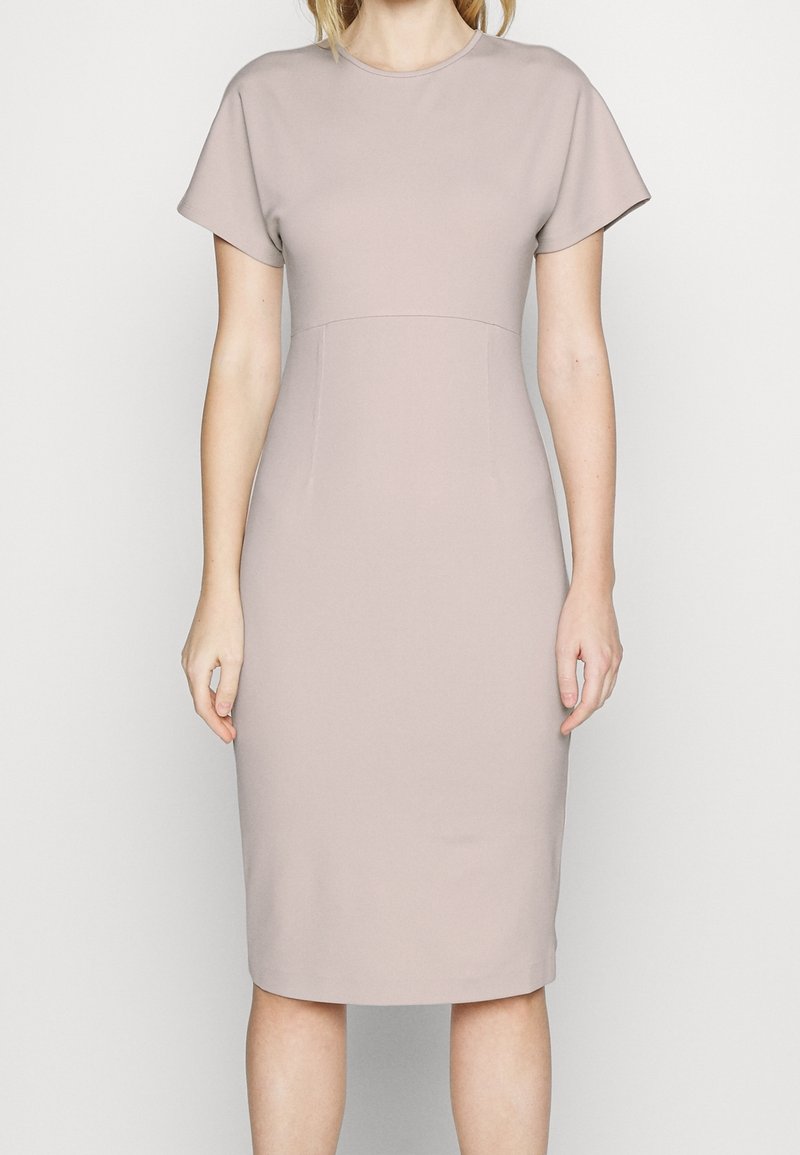 Kortärmad, knälång klänning i ljus beige tyg; figursydd form med rund halsringning och slät yta, inga synliga mönster eller detaljer.