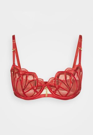 Punane pitsrinnahoidja, millel on geomeetrilised lõiked, lainelised servad ja kuldse tooniga detailid. Reguleeritavad rihmad ja pehme võrkkiudmaterjal mugavuse tagamiseks.