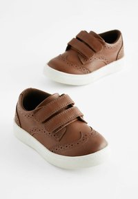 Zapatos de cuero marrón con dos tiras de velcro, suelas de goma blanca y detalles perforados decorativos. Diseño de punta redondeada y corte bajo.