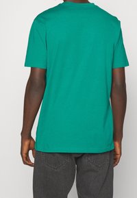 Grøn bomulds-t-shirt med rund halsudskæring, korte ærmer og en afslappet pasform; bagfra ses et glat, udekoreret design.