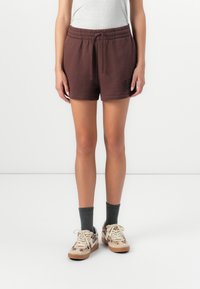 Brune shorts med elastik i taljen og sidelommer har "GAP" logo i sort. Sættes sammen med grå sokker og mønstrede beige sneakers.