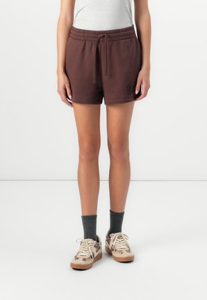 Brune shorts med elastik i taljen og sidelommer har "GAP" logo i sort. Sættes sammen med grå sokker og mønstrede beige sneakers.