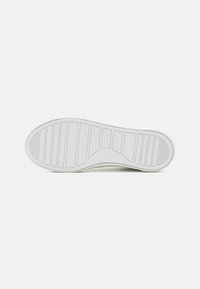 White sneaker outsole with rubber material. Features horizontal and vertical tread patterns for grip and traction. Smooth texture and rounded shape.