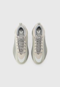 Ljust grå atletiska sneakers med ovandel av mesh, gummisula och rundad tå. Har vadderad krage och kontrasterande detaljer på sidorna.