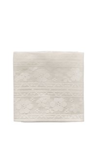 Tissu en dentelle blanche plié avec des motifs floraux et géométriques sur un fond blanc uni.