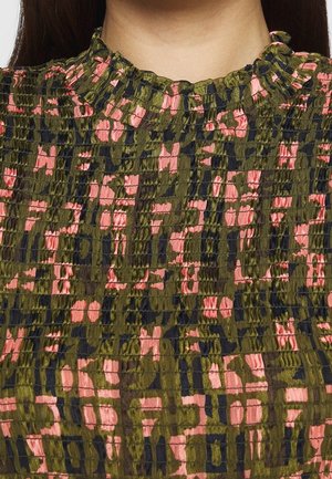 Close-up af en smocket stof-top med høj flæsekant, med et abstrakt mønster i olivengrøn, pink og sort.