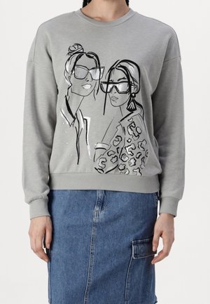 Grijze sweatshirt met zwarte lijntekening van twee vrouwen die oversized zonnebrillen dragen, één met een jas met luipaardprint, gecombineerd met een blauwe denim rok.
