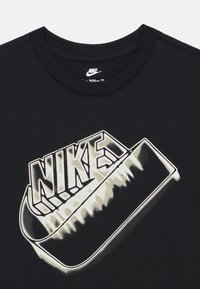 Μαύρο βαμβακερό T-shirt με μεγάλο λευκό λογότυπο Nike με εφέ σκιάς, στρογγυλεμένο ντεκολτέ και κοντά μανίκια.