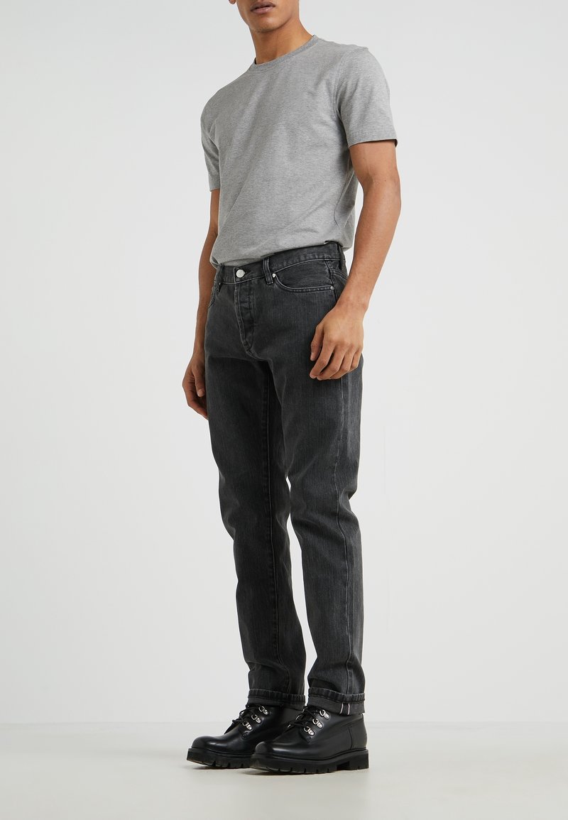 Gray t-shirt with short sleeves paired with black jeans. The jeans feature a classic design with subtle fading and a straight cut. Black boots completed the look.