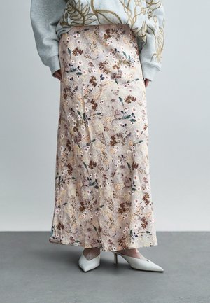 Spódnica midi w kwiatowy wzór w delikatnym beżu, z misternym haftem w odcieniach brązu, zieleni i bieli. Gładka faktura, zestawiona z białymi szpilkami.