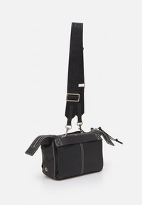 Svart läder crossbody-väska med kontrasterande vit sömnad, dragkedjestängning, justerbar rem och dekorativa hårdvaruaccent. 