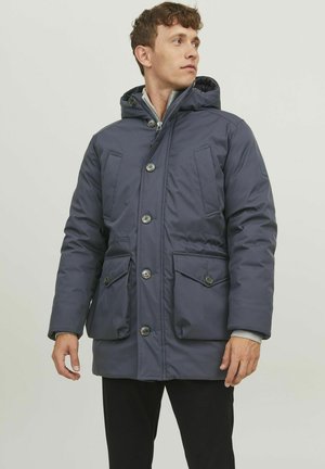 Mørkeblå isoleret parka med lynlås og knaplukninger foran, der har to store frontlommer og en hætte. Glat, holdbart stof.
