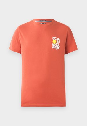 Kortermet t-skjorte i korallfarget bomull. Har et hvitt grafisk trykk med tekst og et smilende ansikt på venstre brystområde. Rund hals.