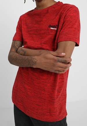 Rotes meliertes T-Shirt mit kurzen Ärmeln, Rundhalsausschnitt und gesticktem Logo auf der Brust. Weicher Stoff und lockere Passform mit leicht verlängertem Rücken.