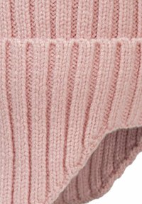 Détail d'un pull en laine rose avec des côtes verticales, une texture douce et un léger repli au niveau de l'ourlet, mettant en valeur un design confortable.