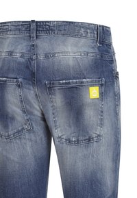 Vaqueros de mezclilla en azul claro con un acabado desgastado. Cuenta con dos bolsillos traseros y una pequeña etiqueta amarilla en el bolsillo derecho.