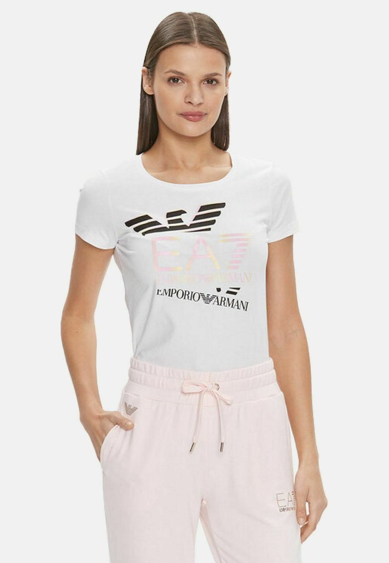 T-shirt bianca in cotone a maniche corte con stampa del logo multicolore. Abbinata a pantaloni della tuta rosa chiaro, caratterizzati da una vita elastica.