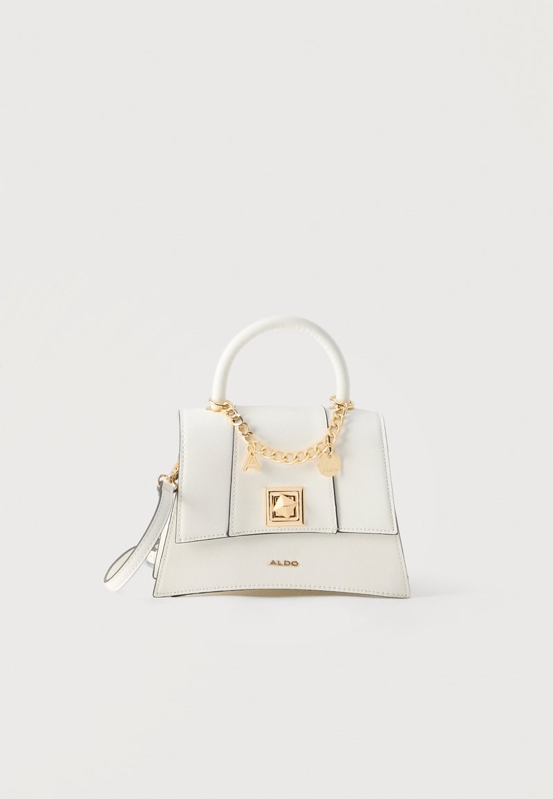 Sac à main structuré blanc avec poignée supérieure, chaîne dorée et détails de breloques, rabat avant avec fermoir carré, et bandoulière poignet sur fond uni.