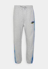 Grå sweatpants i mjukt material, med ett elastiskt midjeband, blå sidostreck och en broderad design på vänster lår.