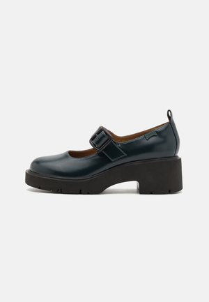 Scarpe Mary Jane in patent turchese con punta tonda, fascia e fibbia, suola platform nera chunky e una finitura leggermente texture.