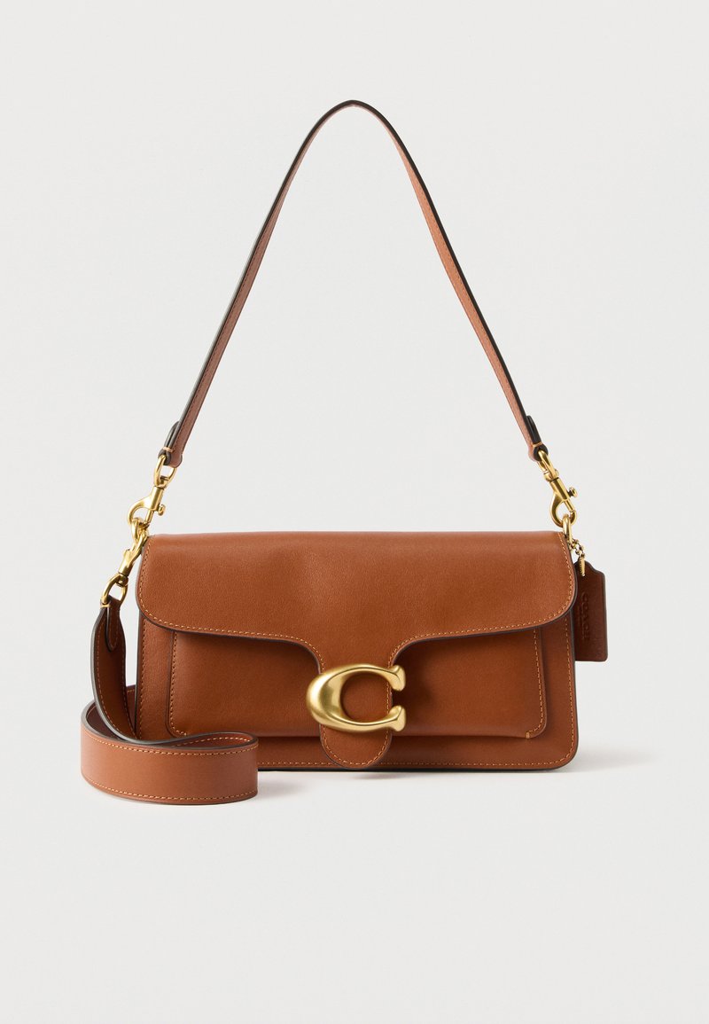 Καφέ δερμάτινη τσάντα ώμου με κούμπωμα "C" σε χρυσό τόνο, αποσπώμενο λουράκι και λείο φινίρισμα σε απλό λευκό φόντο.