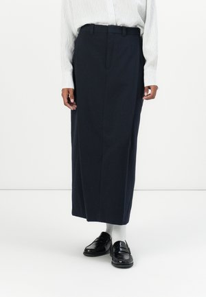 Navy lang skjørt med rett snitt, med frontfolder og beltehemper. Kombinert med svarte loafers og hvite sokker.
