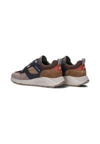 Een paar lage sneakers in bruin, zwart en beige met suède en mesh panelen, dikke witte zolen en merksymbolen op de zijkanten en de hakken.
