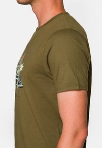 Oliwkowa bawełniana koszulka z krótkimi rękawami, z grafiką przedstawiającą samochód oraz palmy z przodu, z okrągłym dekoltem.