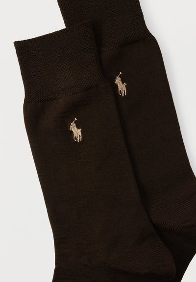 Ζεύγος σκουρόχρωμες καφέ πλεκτές κάλτσες με διπλωμένες μανσέτες και μπεζ κεντημένο λογότυπο ποδοσφαιριστή πόλο κοντά στον αστράγαλο.