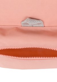 Persikofärgad tygpåse med en texturerad grå dragkedja, med en slät insida och en något strukturerad form.
