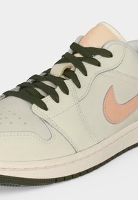 Λευκό και μπεζ ψηλό αθλητικό παπούτσι με πράσινα κορδόνια και ροζ λογότυπο Nike Swoosh στην πλευρά.