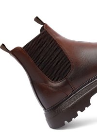 Stivale alla caviglia in pelle marrone con pannelli elastici laterali, tessuto texture e suola in gomma robusta con battistrada pronunciato per una migliore aderenza.