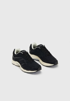 Schwarze Sportschuhe mit Obermaterial aus Mesh und Wildlederelementen. Mit einer gepolsterten weißen Sohle und schwarzen Schnürsenkeln. Abgerundetes Zehen-Design.
