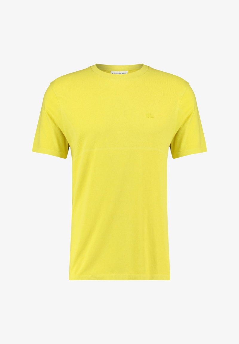 T-shirt jaune à manches courtes en tissu respirant, avec un col rond et un logo discret sur le côté gauche de la poitrine.